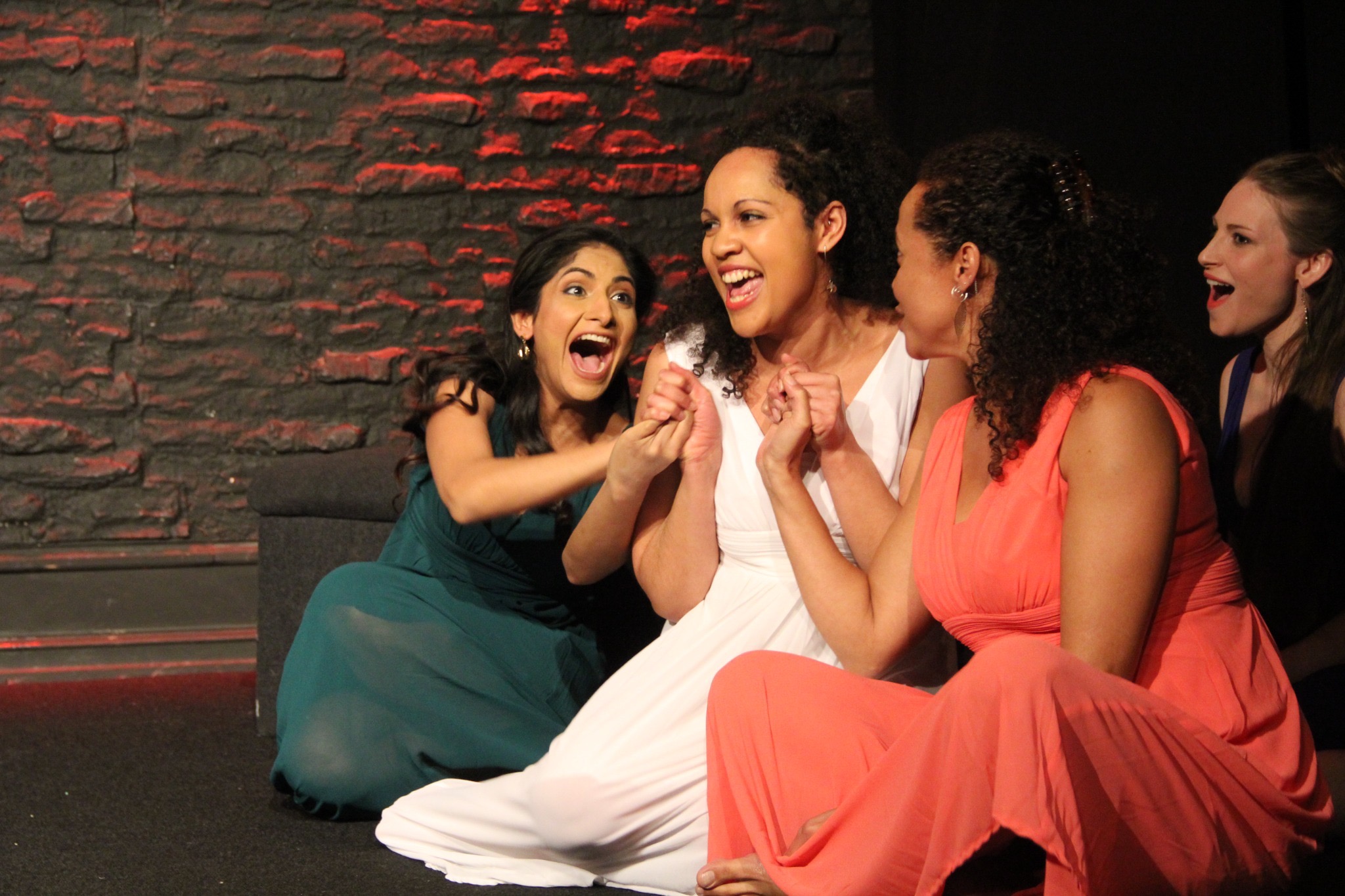 Four women seated together in a burst of laughter and delight.
