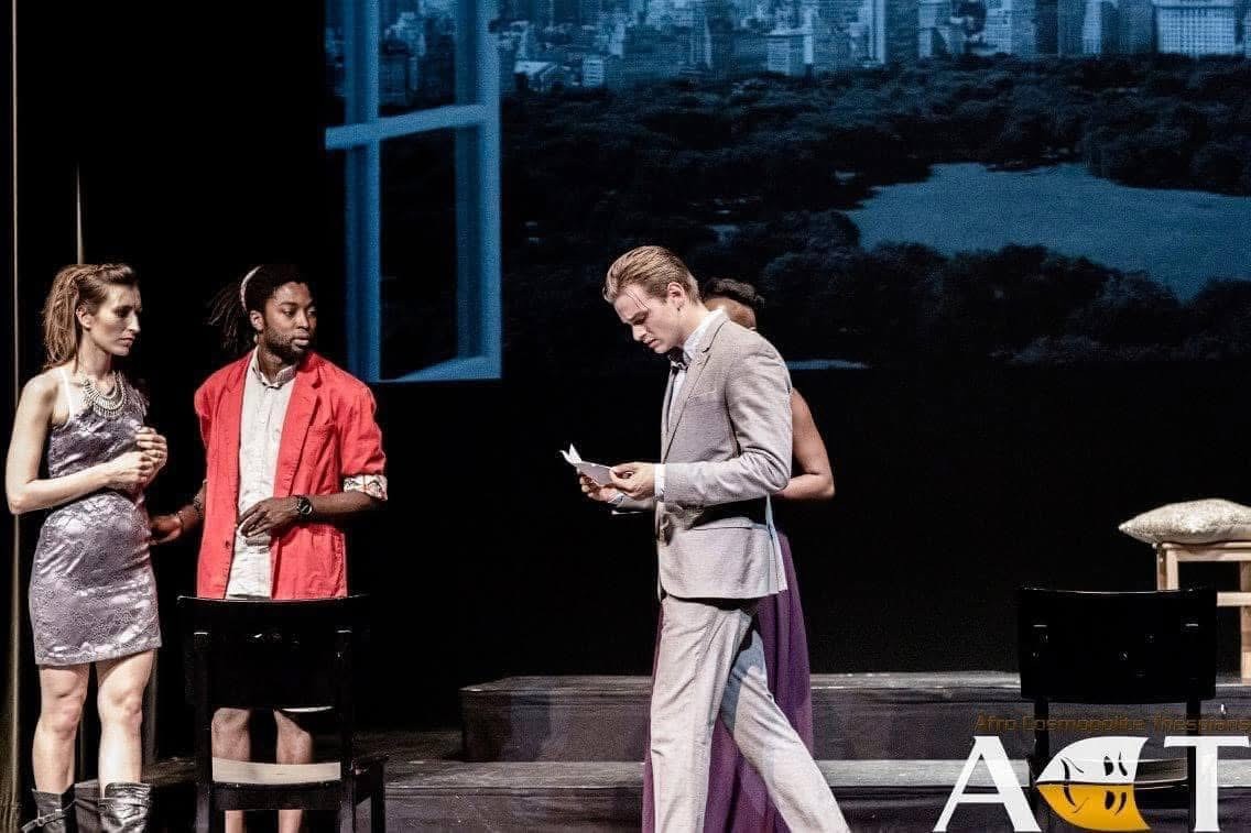 En figur læser fra et papir på scenen i Købmanden i Venedig, mens andre ser til.