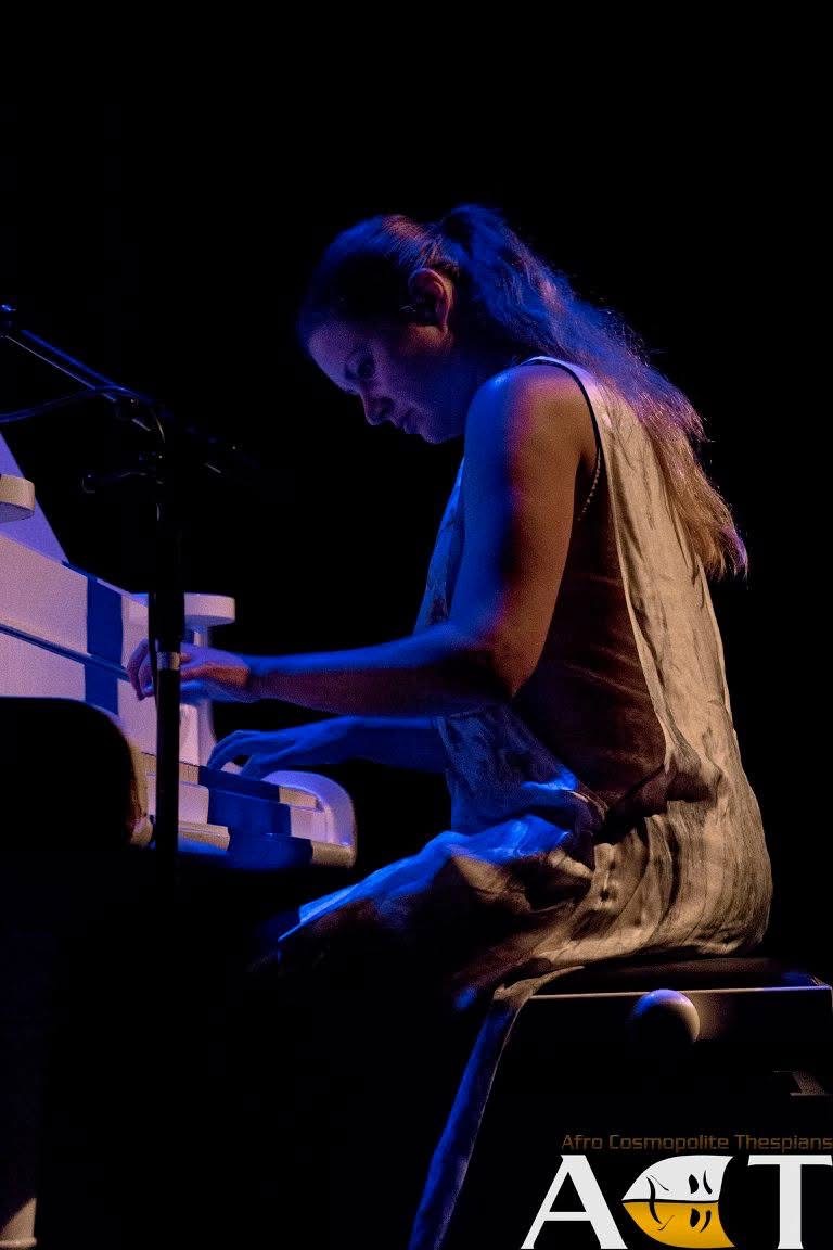 One of the pianists performing the production’s incidental music in The Merchant of Venice under blue stage light at the keyboard.