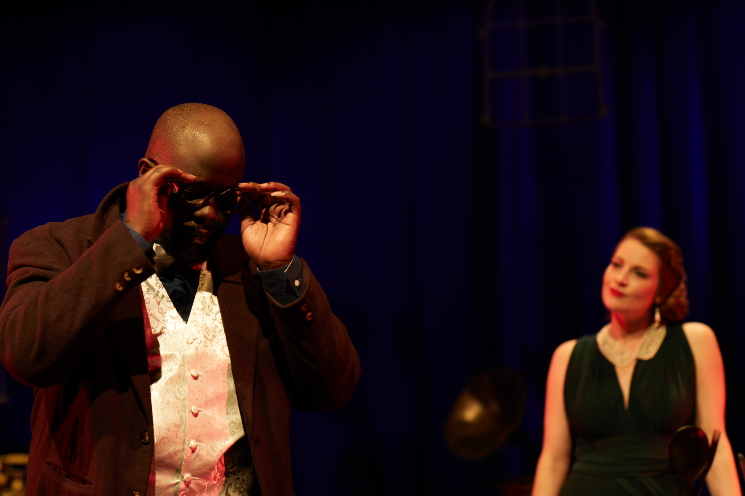 Jean foregrounded as Alice de Janzé studies him across the room.